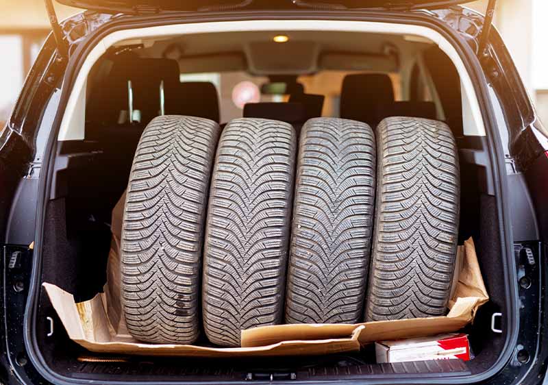 Four spare tires loaded in the back of a pickup truck.